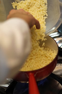 adding cheese to fondue